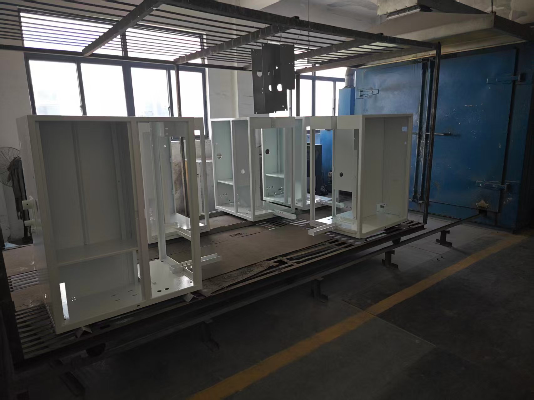 Powder coating line with enclosures on conveyor